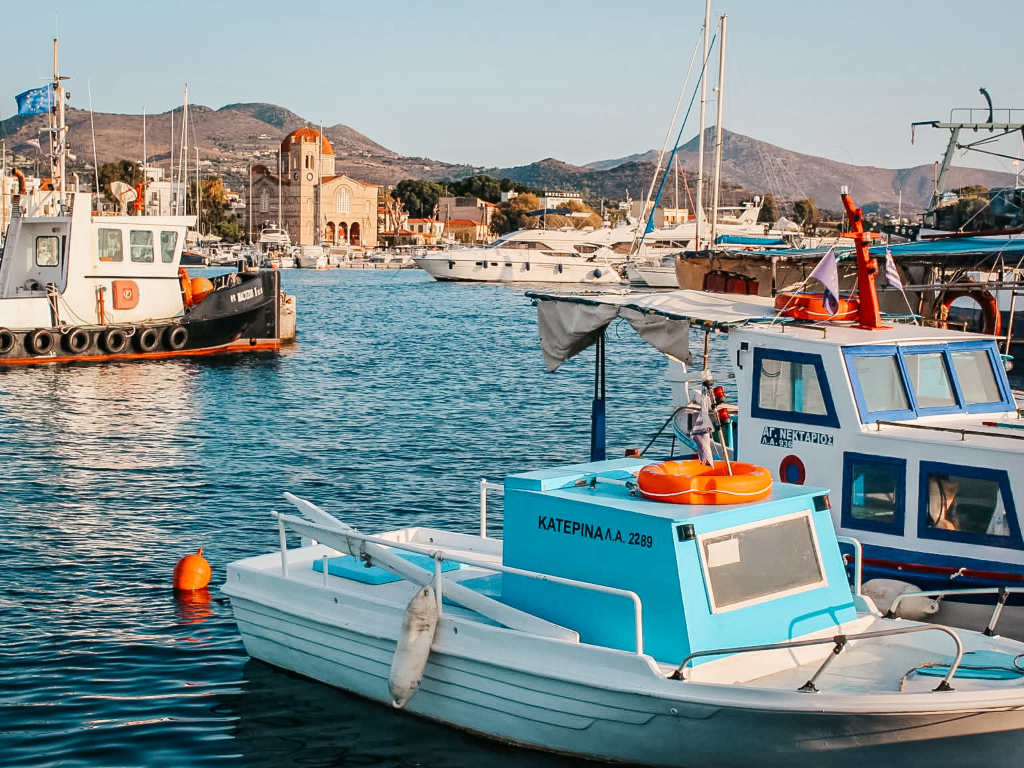 Scatto dal porto di Aegina con barche ormeggiate e sullo sfondo la Chiesa di Isodia Theotokou
